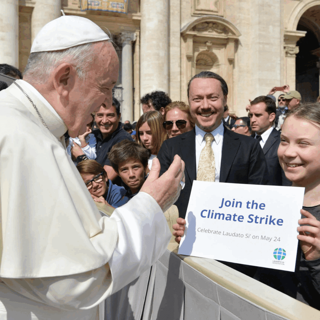 Pope Francis on the left speaking with the teenage climate activist Greta Thunberg in the front row of St Peter's Square among a large crowd