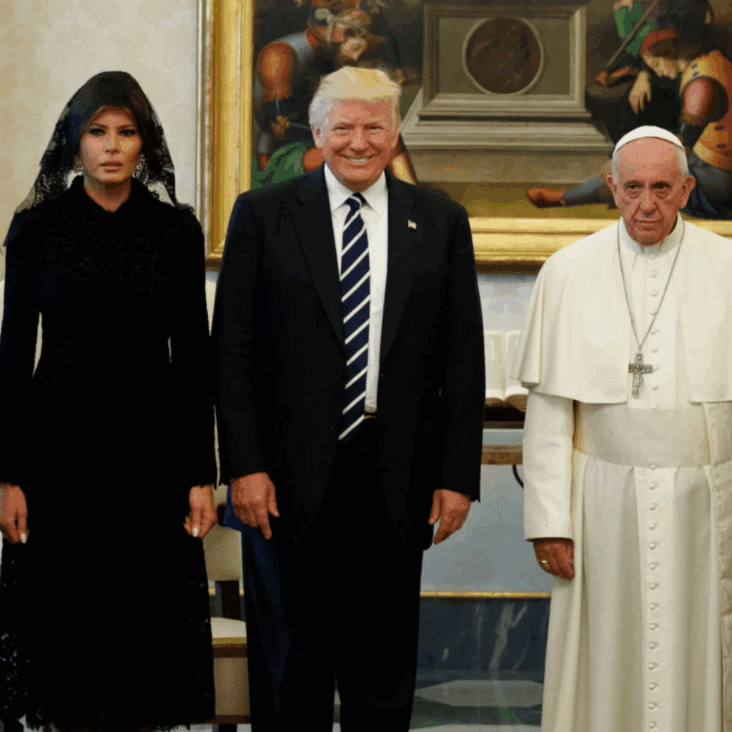 Melania Trump dressed in black and a lace head covering with an expressionless face with Trump to her right grinning and Pope Francis to his right with a stern expression on his face