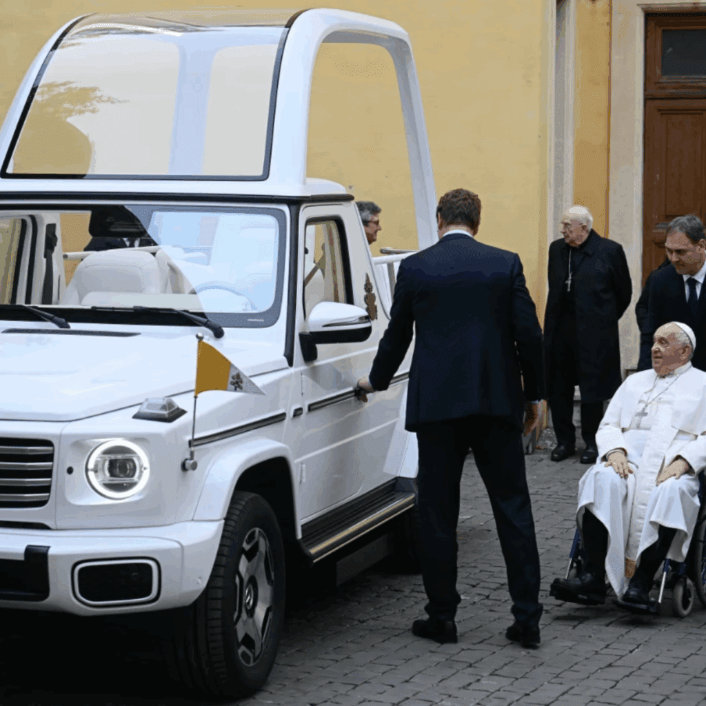 Electric Pope Mobile on left with Pope Francis on a wheel chair on the right